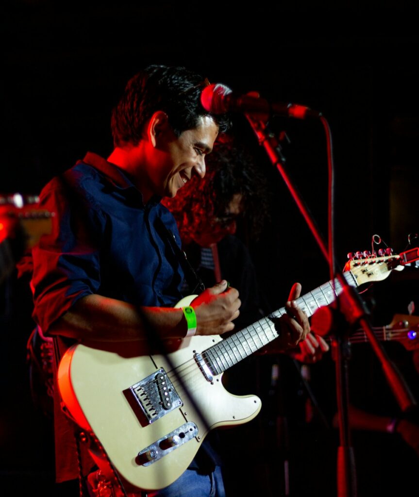 Man playing a white electric guitar on stage